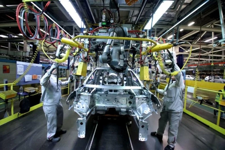 Workers carry out a task on an electric vehicle production line. (Photo: Bangkokpost)