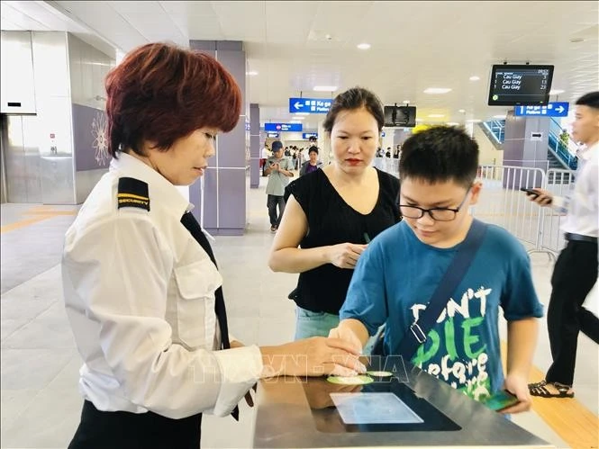 Hanoi Metro staff assist passengers at the ticket gate. (Photo: VNA)