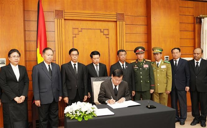 Party General Secretary and President of Laos Thongloun Sisoulith writes in the condolence book. (Photo: VNA)