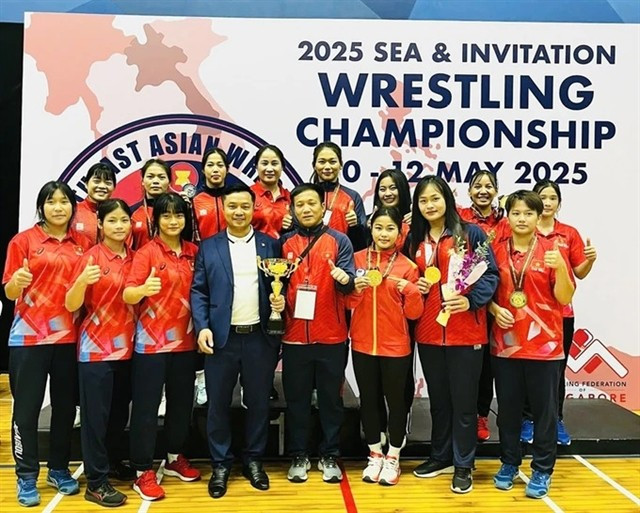 Vietnamese coaches and athletes pose with their golds and trophy from the Southeast Asian and Invitation Wrestling Championships which closed on May 12 in Singapore. (Photo: Vietnam Sports Team)