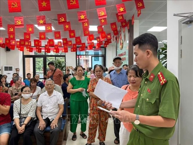 A police officer of Dong Da ward, Hanoi, gives guidance to citizens who come to receive the National Day gifts. (Photo: VNA)