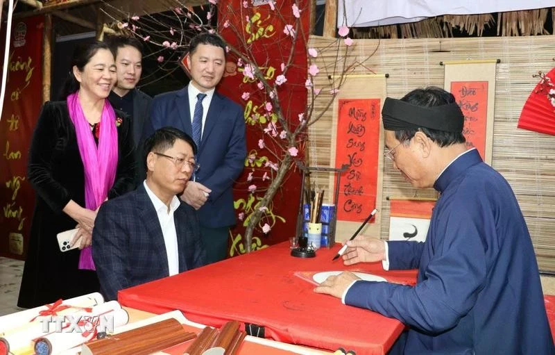 Tourists ask for a calligraphy at a stall in the traditional Tet market in Hoa Lu old quarter. (Photo: VNA)