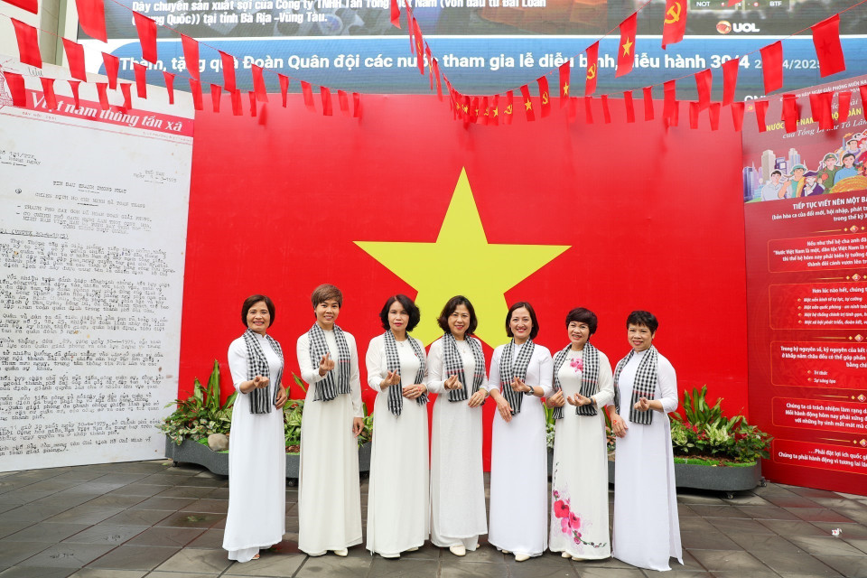 People pose with the national flag at the headquarters of the Vietnam News Agency. (Photo: VNA)