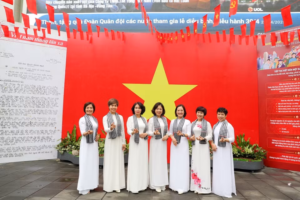 People pose with the national flag at the headquarters of the Vietnam News Agency. (Photo: VNA)