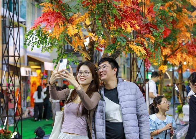 Visitors take photos along the “Hanoi Autumn Street”. (Photo: VNA)
