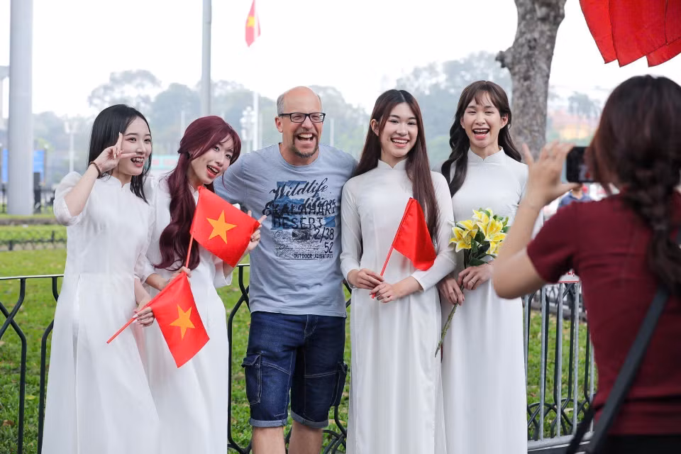 Foreign visitors enjoy taking photos with the Vietnamese flag. (Photo: VNA)