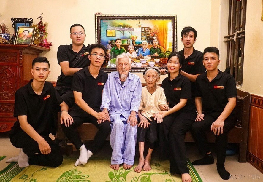 The Skyline photo restoration group presents Heroic Vietnamese Mother Nguyen Thi Ngach with a recreated photo depicting a family reunion meal with her two sons. (Photo: Released by VNA)