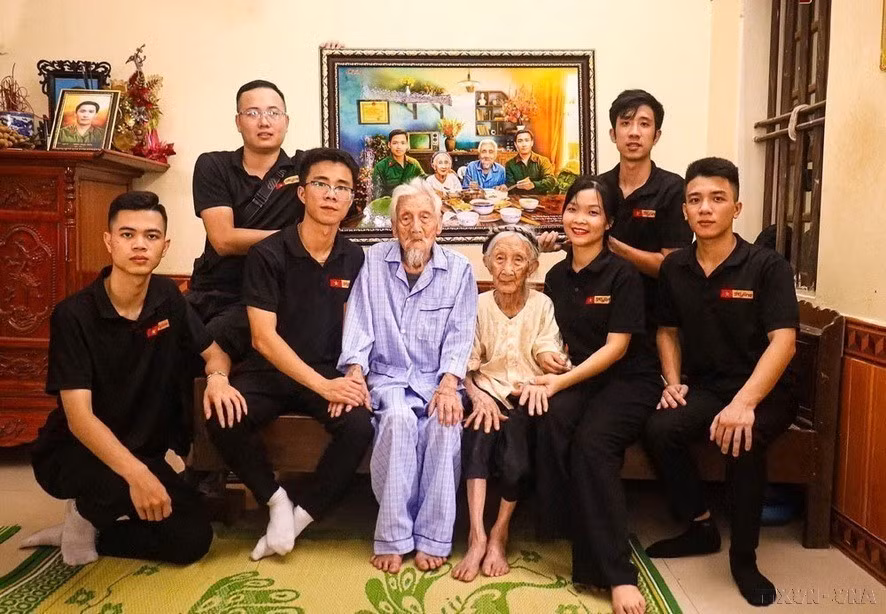 The Skyline photo restoration group presents Heroic Vietnamese Mother Nguyen Thi Ngach with a recreated photo depicting a family reunion meal with her two sons. (Photo: Released by VNA)