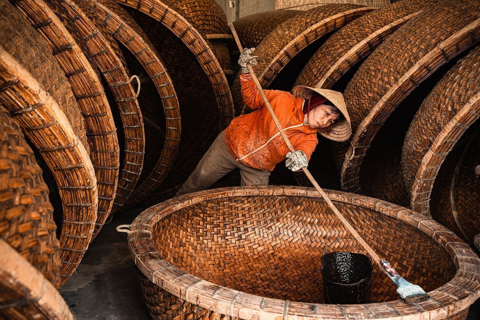 The waterproofing technique uses fresh cow dung mixed with resin from the Dipterocarpaceae tree - a method passed down through generations. This gives the boat its rich color, prevents termite damage, and ensures it lasts 4–5 years in saltwater. (Photo: VNA)