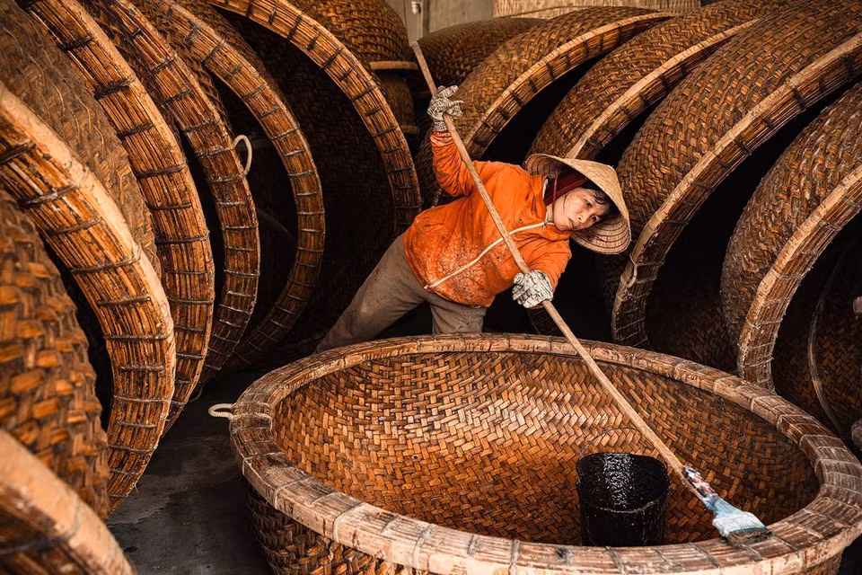 The waterproofing technique uses fresh cow dung mixed with resin from the Dipterocarpaceae tree - a method passed down through generations. This gives the boat its rich color, prevents termite damage, and ensures it lasts 4–5 years in saltwater. (Photo: VNA)