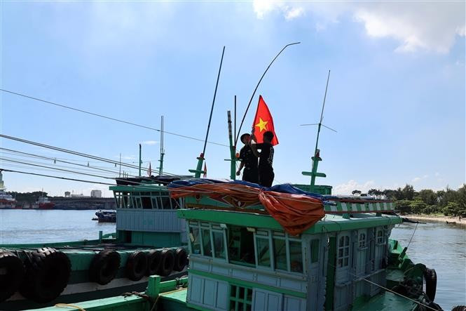 Officers and soldiers from Son Tra Border Guard Station (under Da Nang Border Guard Command) present the national flag to a fishing vessel. (Photo: VNA)