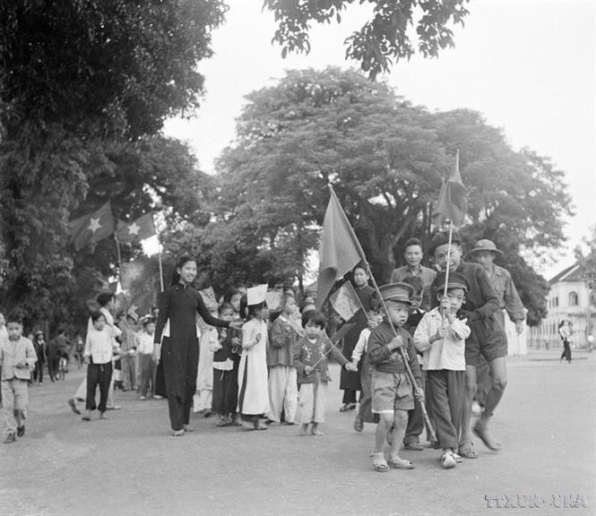 Hanoi children and their families wave flags to greet the soldiers liberating the capital. (File photo: VNA)
