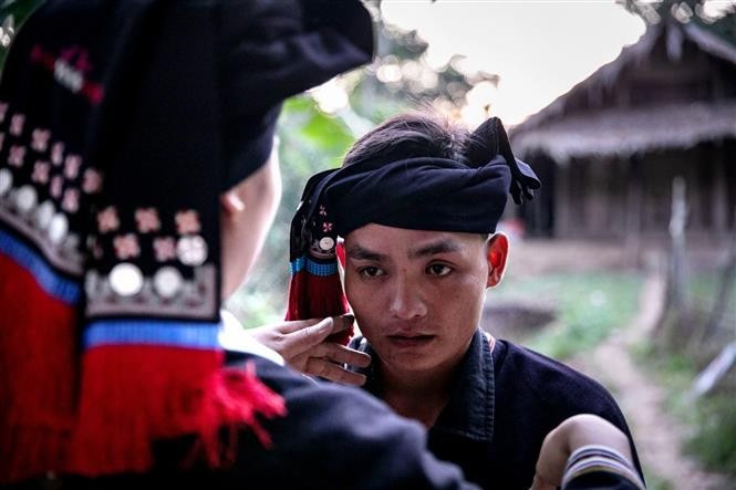 The groom, dressed in traditional attire, offers wine, requests the bride’s hand, and greets her siblings and in-laws. (Photo: VNA)