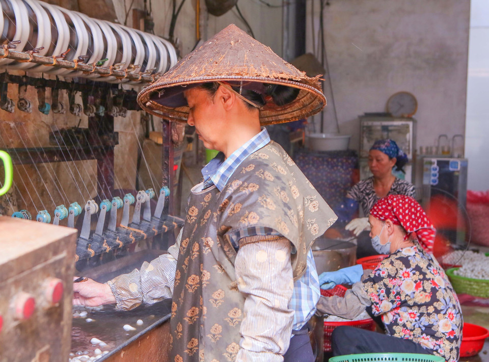 An artisan stirring cocoons, tying threads, and trimming silk filaments. (Photo: VNA)