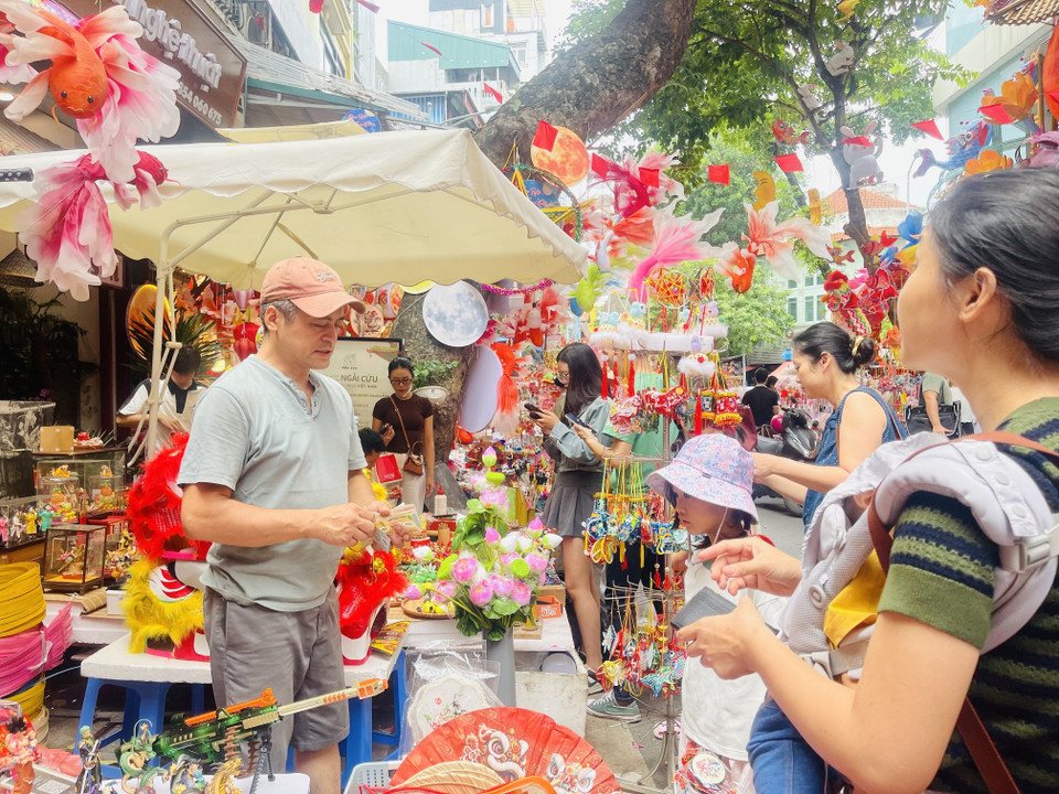 Children are taken by their parents to Hang Ma Street (Hoan Kiem ward, Hanoi) to choose Mid-Autumn toys. (Photo: VNA)