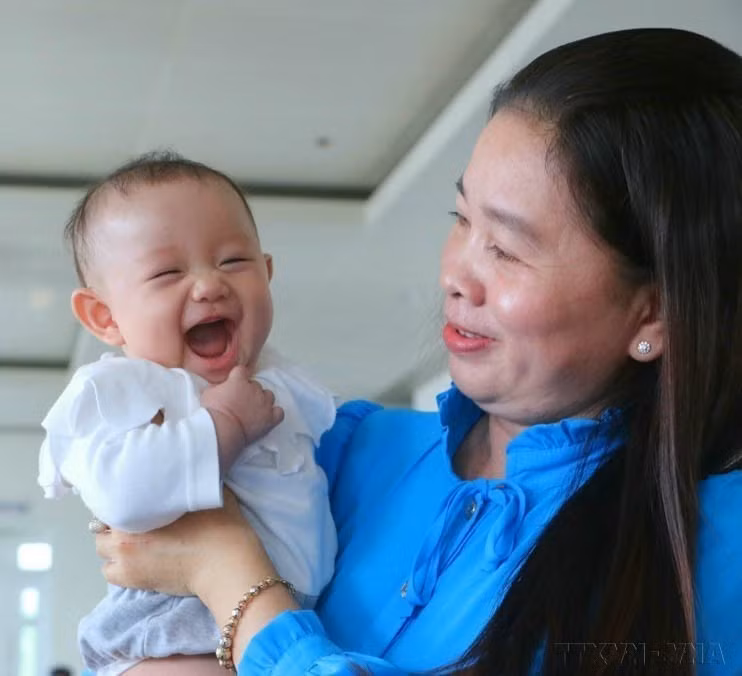 A girl accompanies her mother to receive an award honoring exemplary families with two daughters, held in Hau Giang province (now Can Tho city) (January 5, 2023). (Photo: VNA)