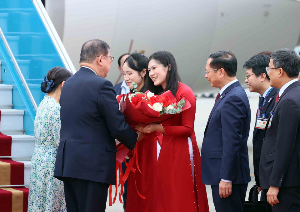 A young woman from Hanoi presents flowers to welcome Japanese Prime Minister Ishiba Shigeru and his spouse on their official visit to Vietnam. (Photo: VNA)
