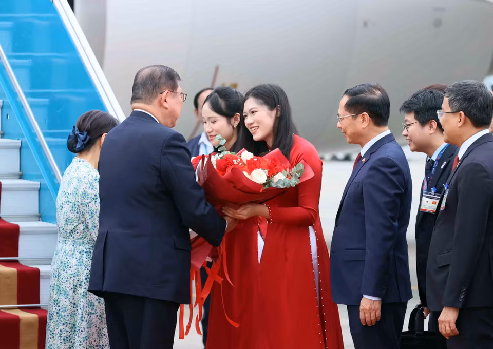 A young woman from Hanoi presents flowers to welcome Japanese Prime Minister Ishiba Shigeru and his spouse on their official visit to Vietnam. (Photo: VNA)