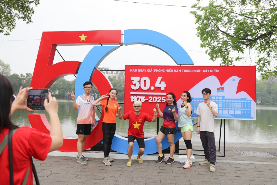 People take photos by Hoan Kiem Lake, commemorating the morning of April 30, 2025 — the 50th anniversary of the Liberation of the South and National Reunification. (Photo: VNA)