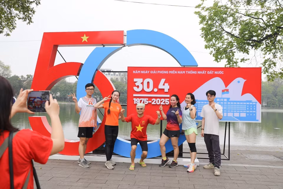 People take photos by Hoan Kiem Lake, commemorating the morning of April 30, 2025 — the 50th anniversary of the Liberation of the South and National Reunification. (Photo: VNA)