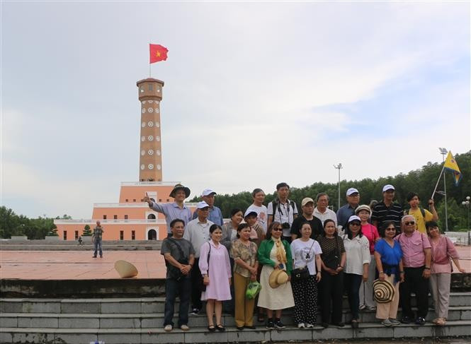 Visitors pose for photos at the Hanoi Flag Tower replica in Mui Ca Mau Tourist Area, Dat Mui commune. (Photo: VNA)
