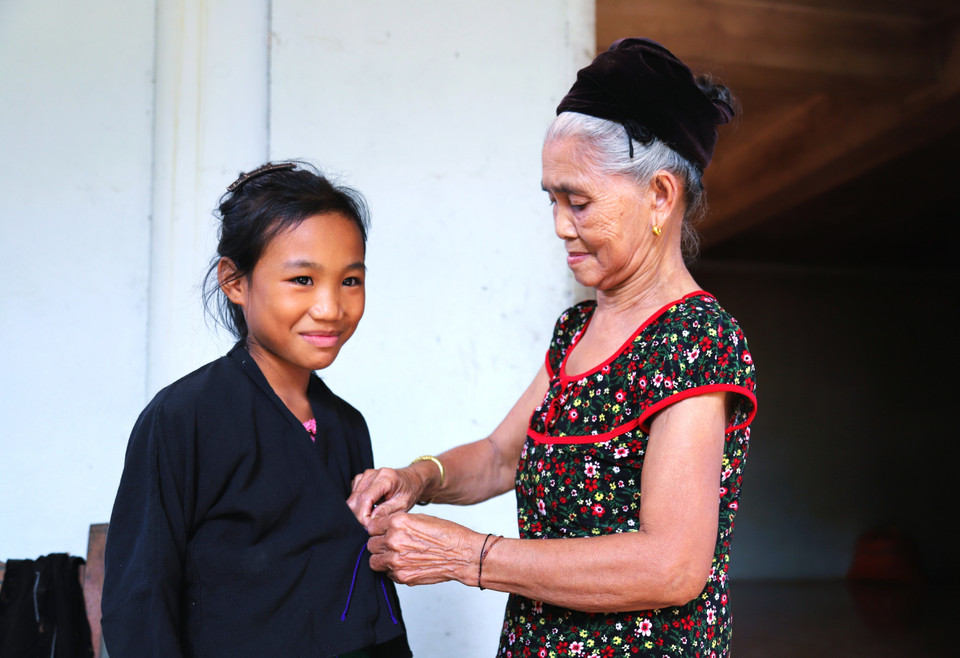 Adults help children dress in traditional attire before attending the ceremony. (Photo: VNA)