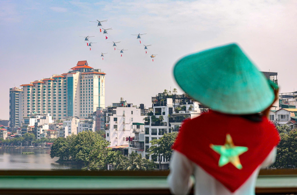 Hanoi residents watch as a fleet of helicopters carrying the Party flag and the national flag rehearse over the city ahead of the A80 event. (Photo: VNA)