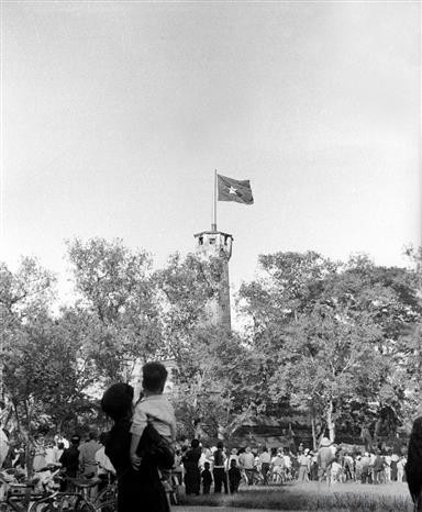 Hanoians joyfully look up at the national flag flying proudly over the Hanoi Flag Tower on the Liberation Day, October 10, 1954. (File photo: VNA)