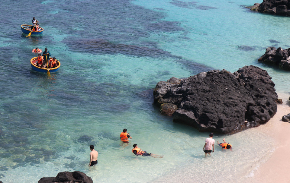 Tourists experience basket boating and swimming in the clear blue water. (Photo: VNA)