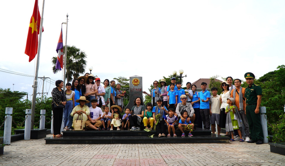 Before joining the flood season field trip, tourists visit and take souvenir photos at a national marker at Thuong Phuoc International Border Gate. (Photo: VNA)