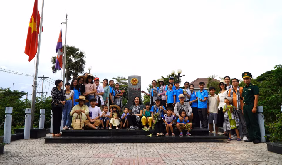 Before joining the flood season field trip, tourists visit and take souvenir photos at a national marker at Thuong Phuoc International Border Gate. (Photo: VNA)
