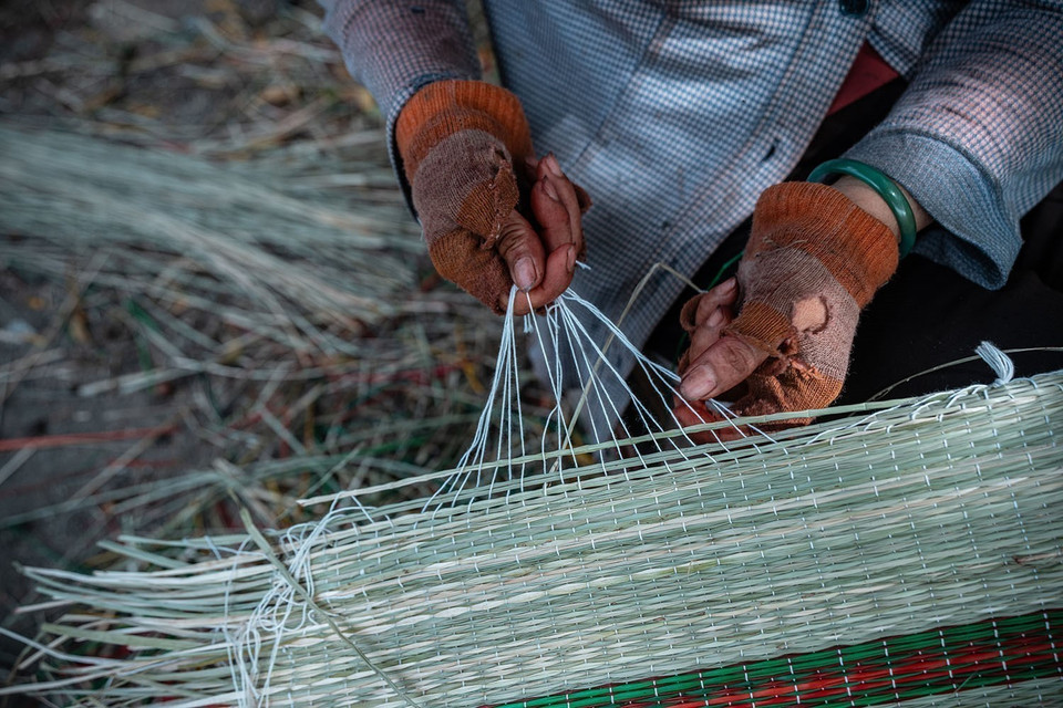 Artisans meticulously tie white threads around the edges of the mats. (Photo: VNA)
