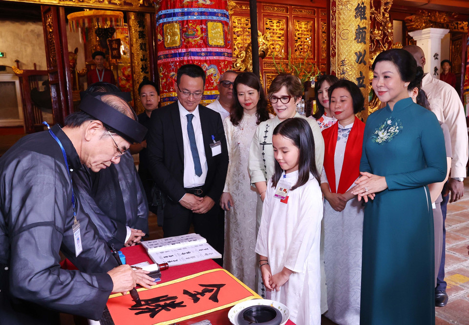 A calligraphy master presents characters to the spouse of the Cuban President. (Photo: VNA)