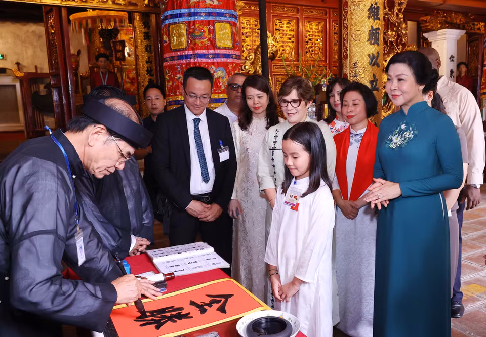 A calligraphy master presents characters to the spouse of the Cuban President. (Photo: VNA)