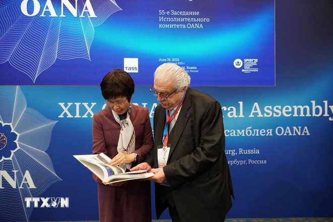 VNA Director General Vu Viet Trang introduces the photo book “100 Years of Vietnam’s Revolutionary Press” to TASS First Deputy Director General Mikhail Gusman. (Photo: VNA)
