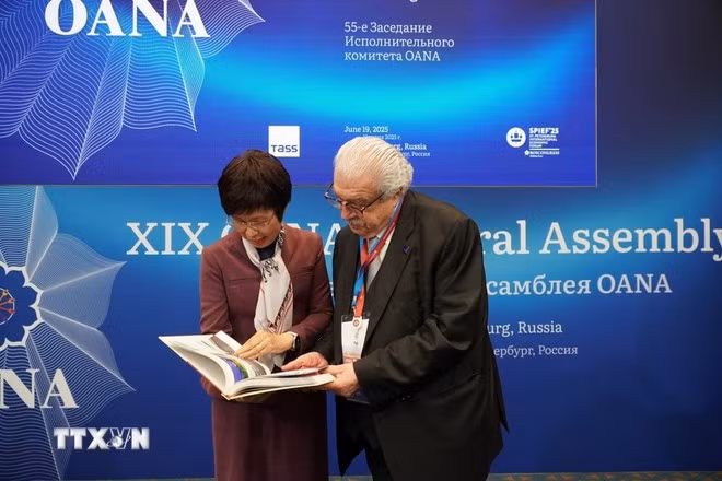 VNA Director General Vu Viet Trang introduces the photo book “100 Years of Vietnam’s Revolutionary Press” to TASS First Deputy Director General Mikhail Gusman. (Photo: VNA)