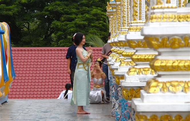 Visitors in traditional Khmer attire take photos at the pagoda. (Photo: VNA)