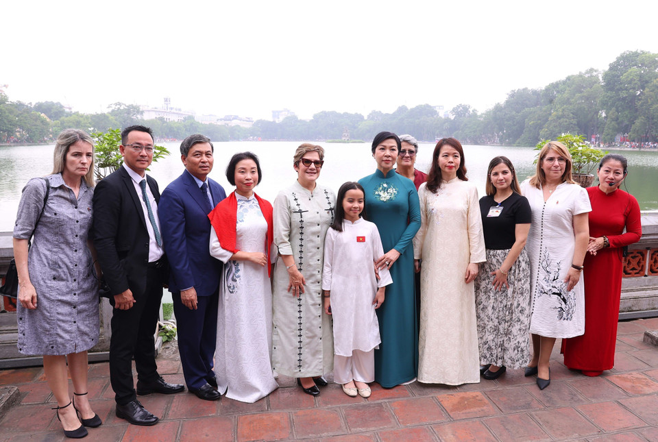 The two spouses pose for a photo with delegation members by Hoan Kiem Lake. (Photo: VNA)