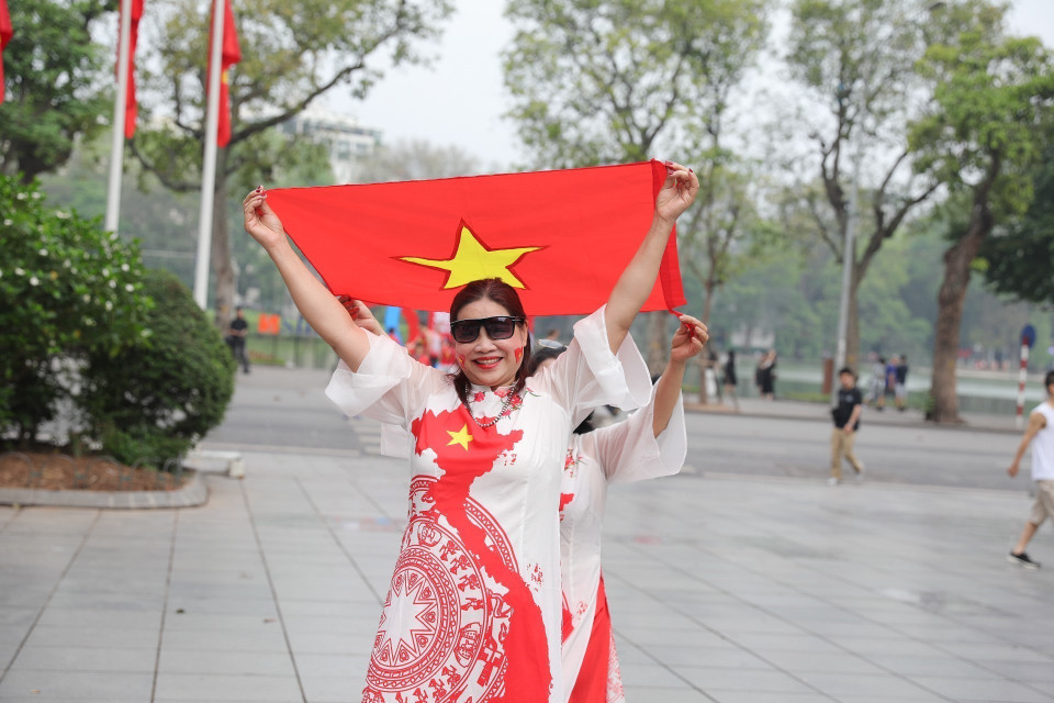 Capital’s residents take photos with the national flag on the morning of April 30, 2025. (Photo: VNA)