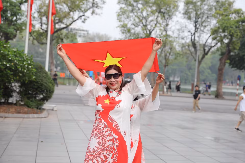 Capital’s residents take photos with the national flag on the morning of April 30, 2025. (Photo: VNA)