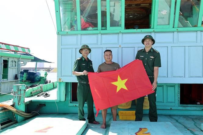 Officers and soldiers from Son Tra Border Guard Station (under Da Nang Border Guard Command) present the national flag to a fishing vessel, reminding fishermen to strictly observe the law and uphold the country’s positive image. (Photo: VNA)