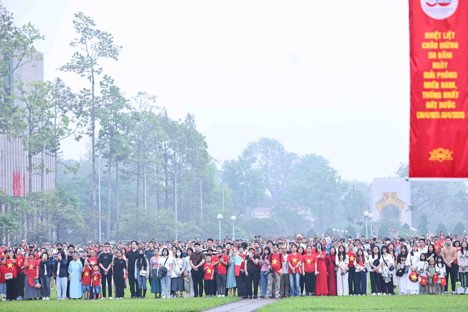 From early morning, people gather at Ba Dinh Square to witness the sacred flag-raising ceremony marking the 50th anniversary of the liberation of the South and national reunification. (Photo: VNA)