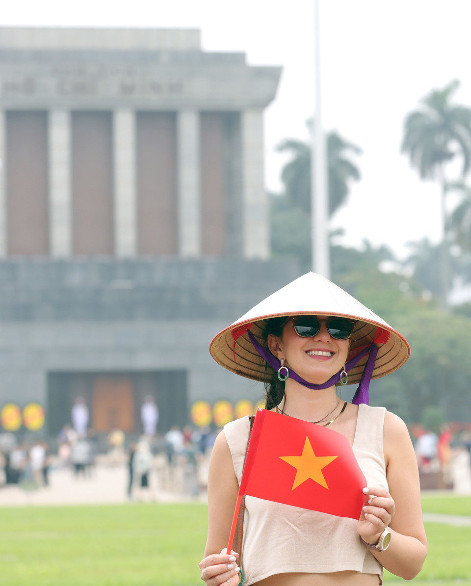 Foreign tourists enjoy taking photos with the Vietnamese national flag. (Photo: VNA)