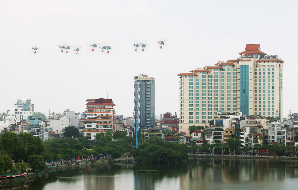 A formation of 10 Air Force helicopters flies carrying the Party flag and the national flag. (Photo: Pham Kien - VNA)