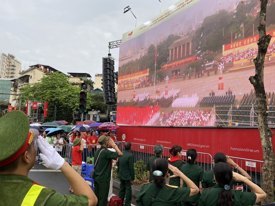 People in the Cua Nam area perform the flag-raising ceremony via live broadcast. (Photo: Vu Sinh - VNA)