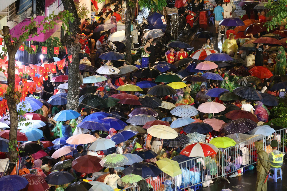 People brave the rain waiting for the National Day full-dress parade rehearsal. Photo: Cong Dat - VNA