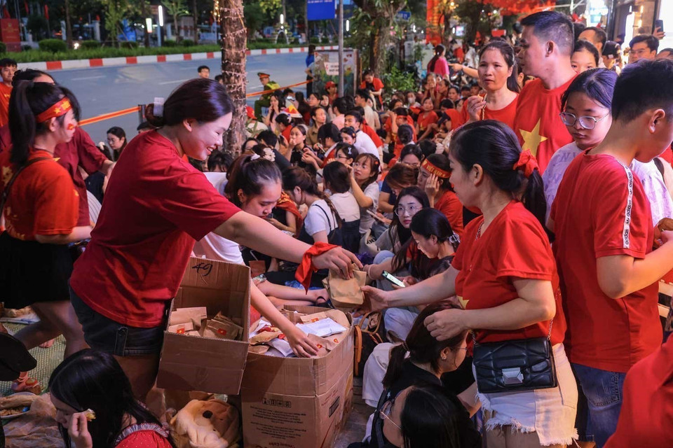 Residents voluntarily share food with one another while staying up on Van Cao Street on the night of August 29 to watch the full-dress parade rehearsal. Photo: Hoang Hieu - VNA