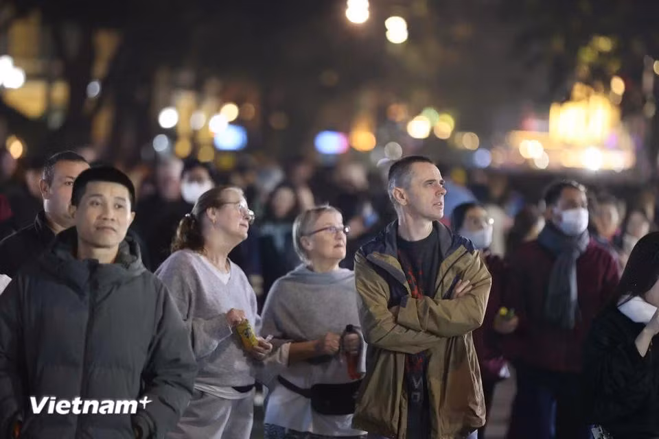 On the evening of December 31, 2024, large crowds of locals and international visitors flocked to Hoan Kiem Lake to soak in the festive atmosphere. They celebrated the final moments of the year while looking forward to a fresh start in 2025. In the photo: Many international tourists join the festivities, sharing that they chose Vietnam for its peace and beauty as the perfect place to ring in the New Year. (Photo: Hoai Nam/Vietnam+)