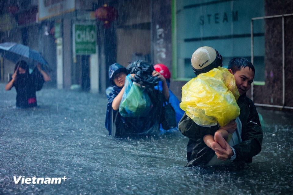 Parents struggle to pick up their children from school through the floodwaters. (Photo: Hoai Nam/Vietnam+)