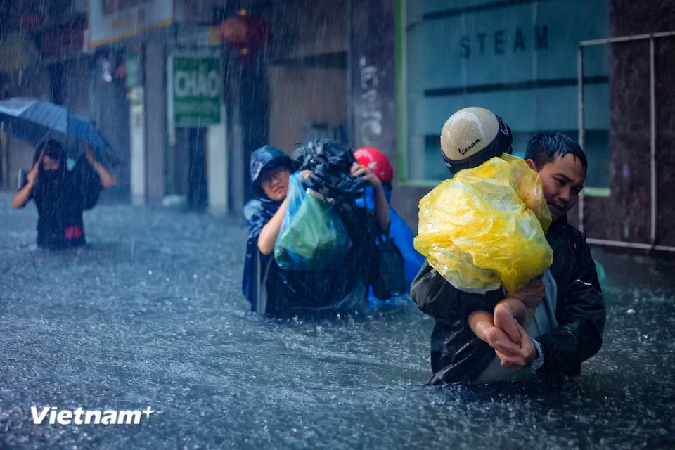 Parents struggle to pick up their children from school through the floodwaters. (Photo: Hoai Nam/Vietnam+)